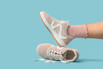 Leg of woman in sock with stylish sneakers on blue background