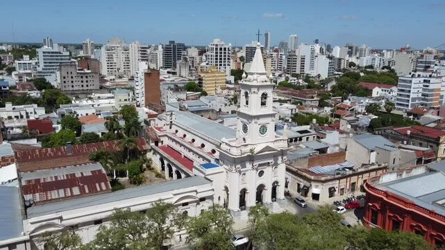 Stunning aerial shot with a drone moving away from the belfry and clock tower of the historic Our Lady of Mercy Church in Corrientes Capital, on a sunny day. Revealing its architecture and surrounding
