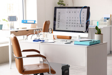 Computer monitor with calendar and doctor's supplies on desk in medical office
