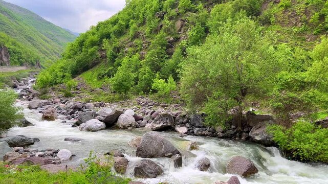 A picturesque mountain stream flowing through rocky terrain, surrounded by vibrant greenery. This video is perfect for showcasing eco-tourism, nature conservation, and adventure content. Ideal for hig