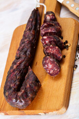 French sort of dry sausage (saucisson sec) from minced pork with liver on wooden surface