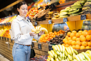 Woman shopping in grocery supermarket - choosing fruit bananas