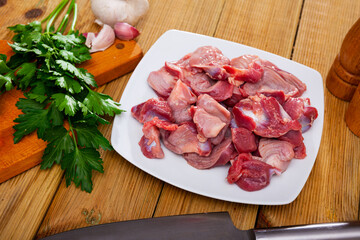 Ingredients for cooking. Raw chicken gizzards with garlic, spices and herbs on wooden table