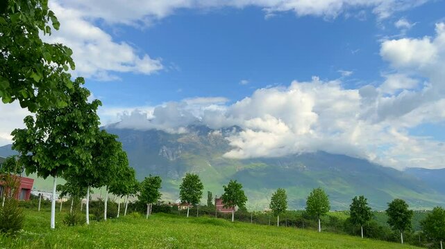 A breathtaking mountain view with green fields and a clear blue sky. Ideal for content related to travel, nature, outdoor exploration, and eco-friendly tourism. This video is perfect for showcasing th