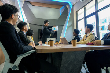 Professional manager leads a discussion with multicultural team, strategizing company growth at an office meeting room.