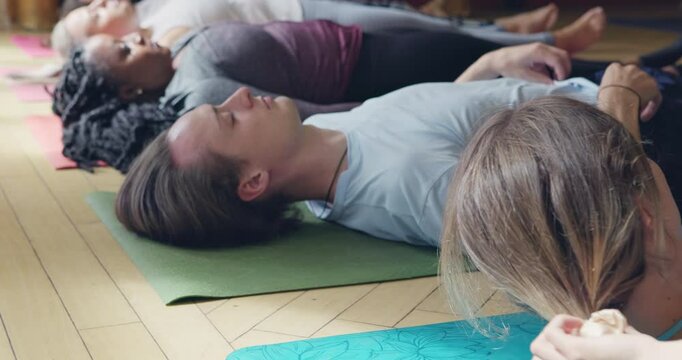 Meditation, yoga class and people in corpse pose at gym, relax and peace in mindfulness. Zen, calm group and dead body exercise on floor, holistic training or workout for fitness, wellness and health
