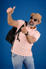 Indian middle age handsome Caucasian man wearing light pink shirt, hat, sunglasses posing against...