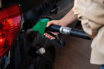 Closeup shot of woman hand filling up the gas tank of a black car 