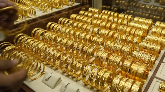 Large collection of shiny gold bangles displayed in a jewelry store showcase