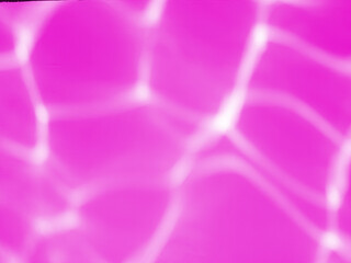 Light reflects on the water surface on the pink wall and blurs.