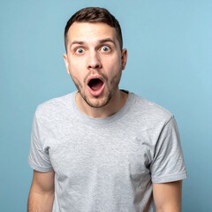 大きく見開いた目と口元が印象的な20代白人男性のブルーグレー背景ショット

