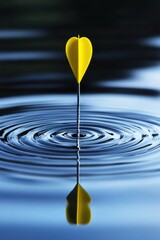 Precise yellow dart piercing water surface creating ripples in blue liquid backdrop perfect aim and focus concept artistic shot for stock photo use