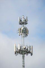Multiple wireless carriers collocated on a metal monopole tower with antennas against a blue and...
