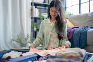 Happy asian Woman packing suitcase for travel planning preparing vacation  in winter.