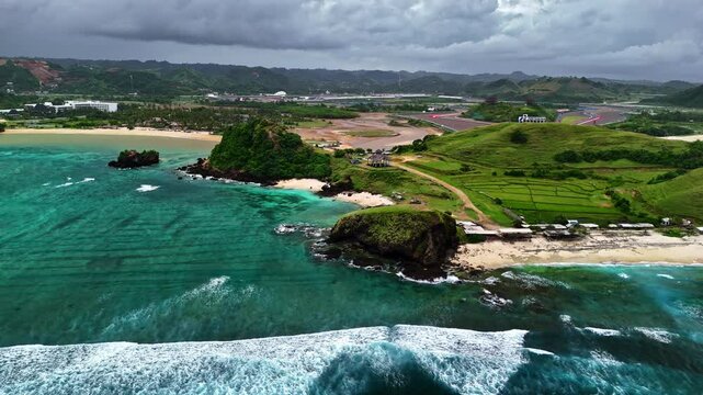 Lush green hills meet turquoise waters at Pantai Seger beach, Kuta Lombok
