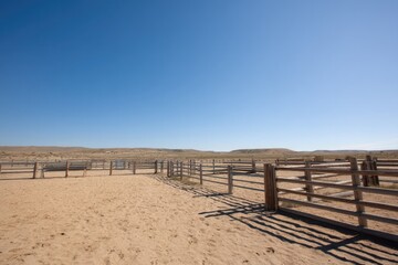 empty rodeo arena with fenced enclosure in sandy landscape minimalistic clear blue sky extensive copy space