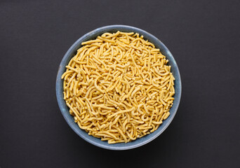 Indian snacks called Bhujia Sev or Medium Sev serve in bowl isolated on dark Background 