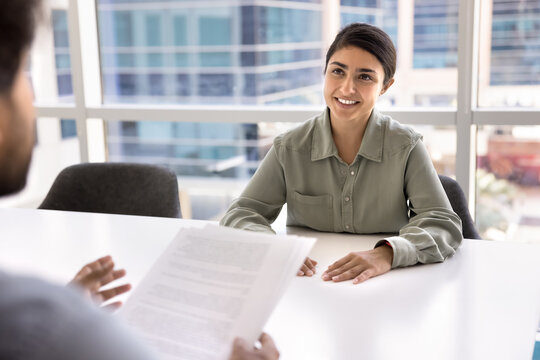 Young Indian woman applicant sit at table in modern office during job interview. Formal meeting between two businesspeople, discuss contract terms and conditions. Confidence, ambition, career growth