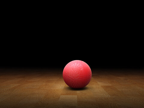 Classic red dodgeball ball, rubber ball on wooden floor, black background.