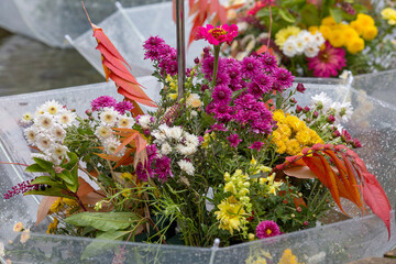 an original composition of bright autumn flowers in a bouquet of a crystal umbrella in daylight