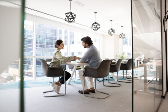 Two businesspeople professionals finalize formal meeting in modern boardroom with handshake gesture, express mutual respect, gratitude for collaboration, successful negotiation outcome. Business, deal