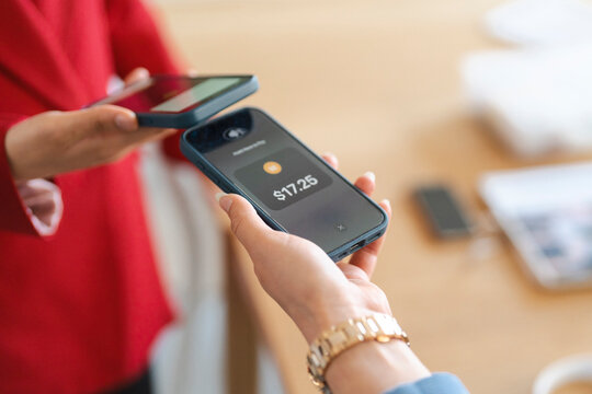 A customer is paying $17.25 with their phone. The cashier is holding their phone to accept the payment. Contactless payments are a fast and easy way to pay.
