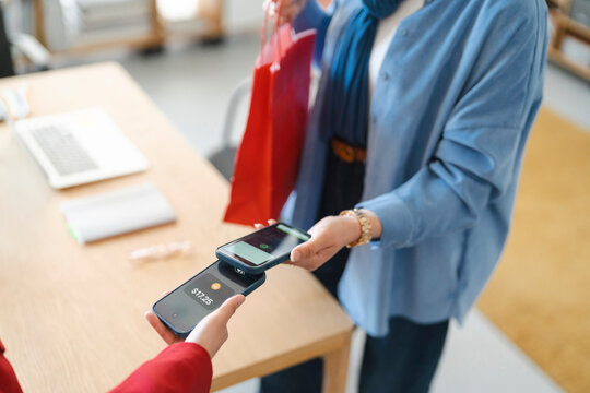 Two people are using their phones to make a tap to pay mobile contactless payment.