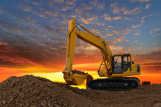 Crawler excavator with are digging the soil in the construction site with blue sky and orange fluffy clouds ,on the  last light sunset background.