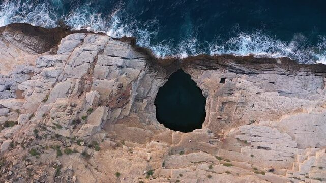 Aerial slow motion view of Giola natural pool near the Mediterranean seaside. Waves crushing the shoreline. Thassos island, Greece