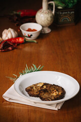 empal gepuk, indonesian style sweet and spicy fried beef dish on white plate and wooden background