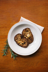 empal gepuk, indonesian style sweet and spicy fried beef dish on white plate, napkin and wooden background