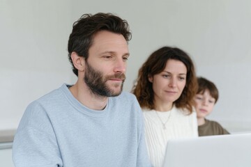 modern family sits around minimalistic white table collaboratively planning their finances using laptop and tablets