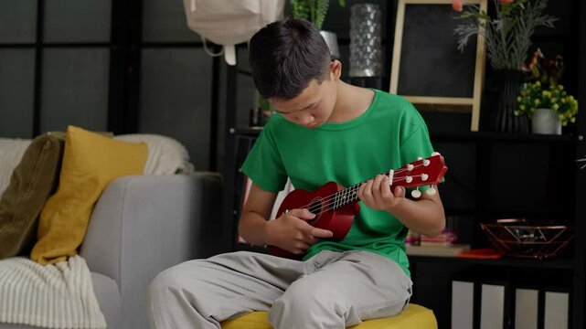 Asian boy learning to play ukulele