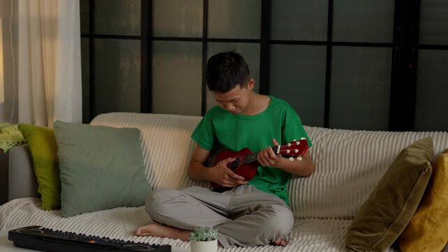Asian boy learning to play ukulele