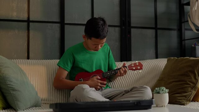 Asian boy learning to play ukulele