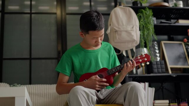 Asian boy learning to play ukulele