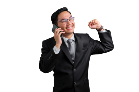 Happy young Asian businessman celebrating success while talking on the phone, fist raised, smiling and excited, isolated on transparent background