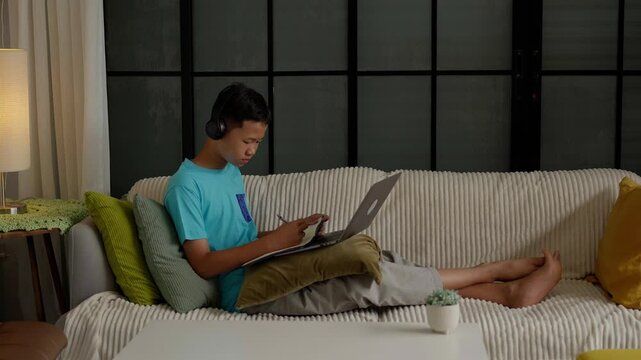 Asian boy studies online on laptop at home