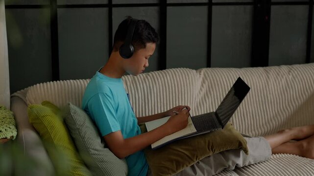 Asian boy studies online on laptop at home