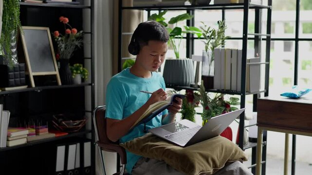 Asian boy studies online on laptop at home