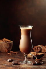 Pieces of dark chocolate fall into a glass of cocoa drink.