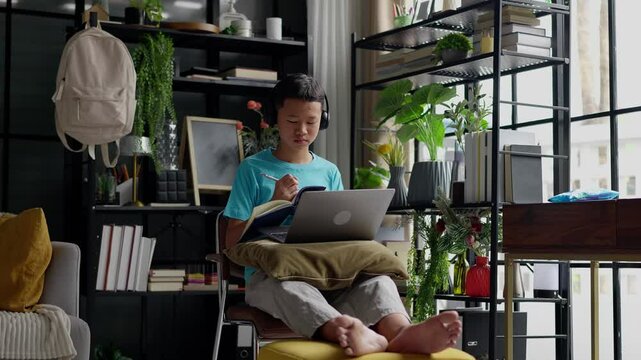 Asian boy studies online on laptop at home