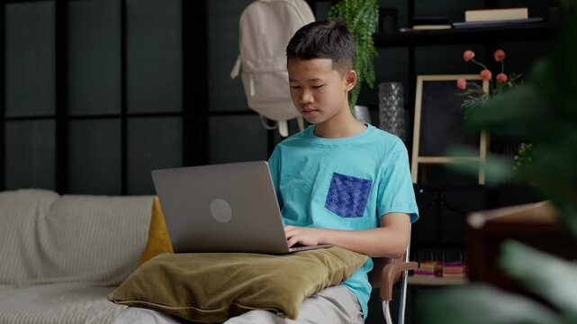 Asian boy studies online on laptop at home