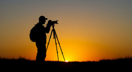 Silhouette of a photographer taking pictures at sunset golden hour capturing the beautiful scenery outdoors