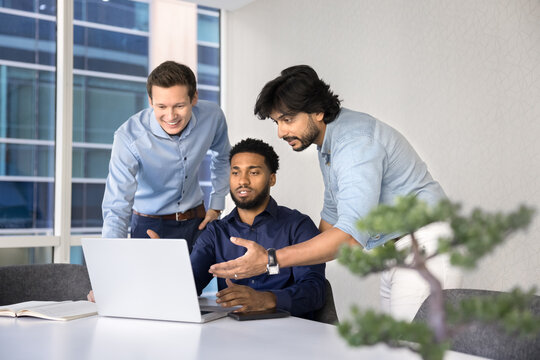 Three skilled professionals, looking at laptop screen, leading discussion about new software, review new innovative business platform, exchanging point, opinion and insights, developing start up ideas