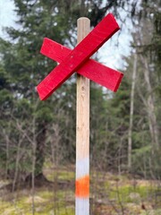 Red wooden cross is a sign for walking trail in the mountains