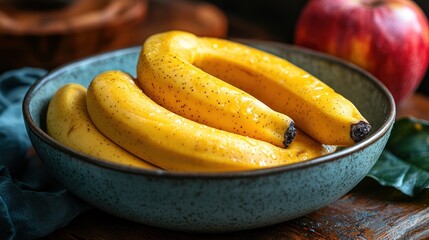 Golden Delight: Ripe Bananas in a Blue Bowl with an Apple in the Back
