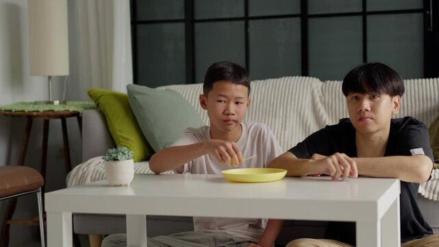 Brother sitting and eating snacks at home.