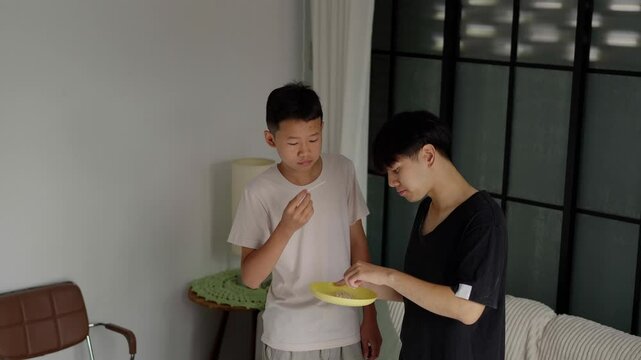 Brother sitting and eating snacks at home.