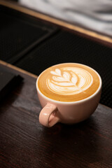 A Cafe Latte with art sits on counter vertical